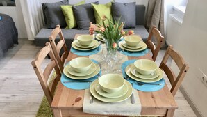 A dining table set with green plates, blue placemats, and a vase of flowers. - Johansson Apartments Vienna (Vienna)