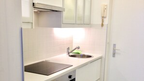 A compact kitchen with white cabinets, a stainless steel sink, and a built-in oven. - Johansson Apartments Vienna (Vienna)