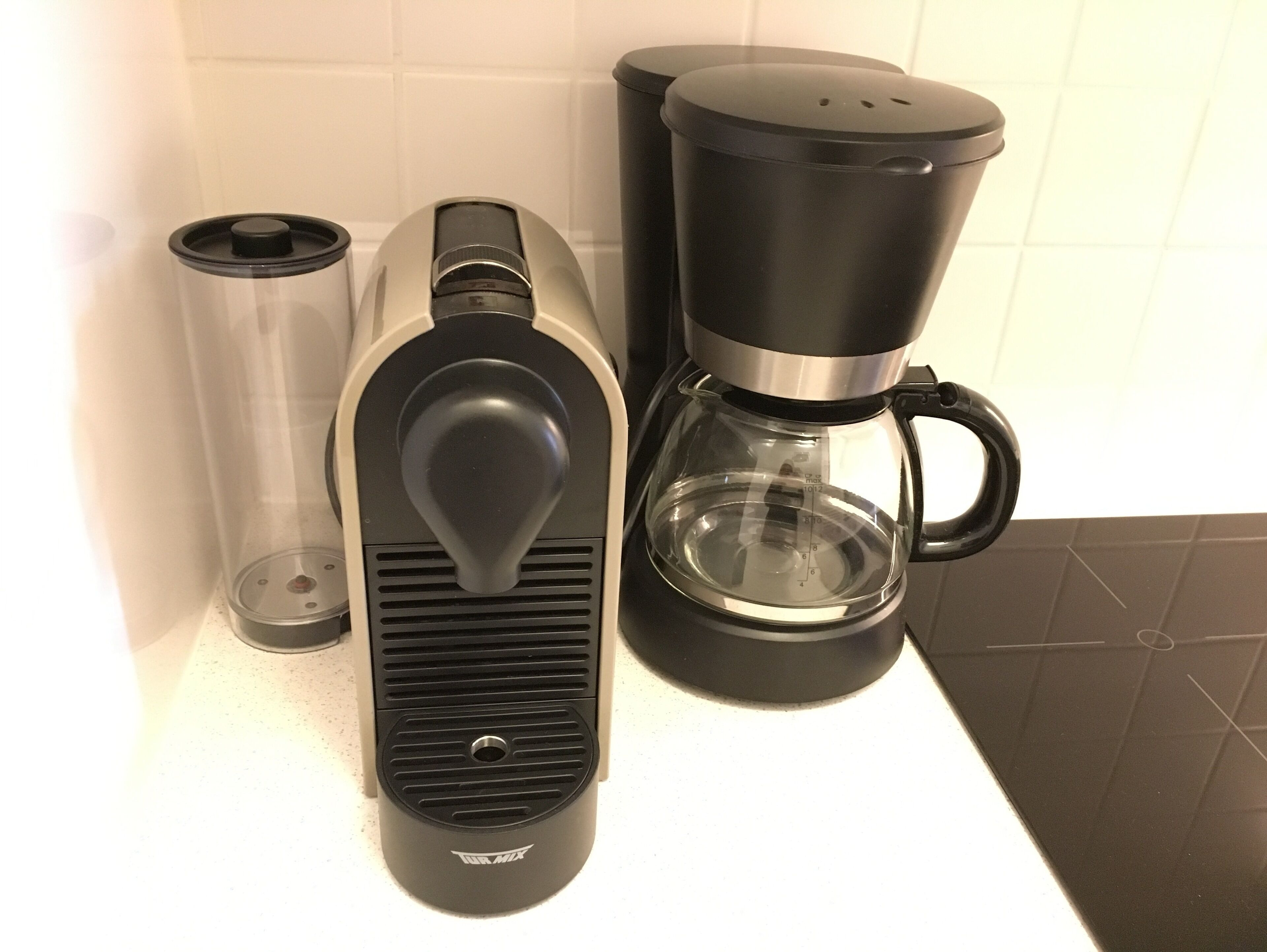 Eine Kaffeemaschine mit transparentem Wasserbehälter, Auffangbehälter für Tropfen und Kaffeekanne mit schwarzem Griff.
