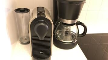 Eine Kaffeemaschine mit transparentem Wasserbehälter, Auffangbehälter für Tropfen und Kaffeekanne mit schwarzem Griff.