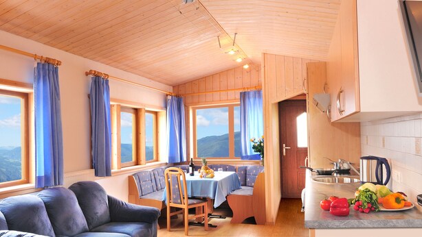 Ett mysigt rum med en soffa, ett matbord och ett köksutrymme med utsikt över bergen.