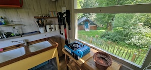 A kitchen with a gas stove, a window with a view of a house and garden, and various kitchen utensils on the counter. - "Sleeping Beauty" idyllically situated pack wagon, accommodation close to nature in the Westerwald (Hundsdorf)