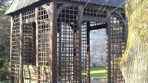 A gazebo with a thatched roof, wooden lattice walls, and a bench. - cottage of the Small Mass (Amboise)