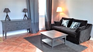 A living room with a grey sofa, two lamps, a coffee table, and a grey console table with lamps. - cottage of the Small Mass (Amboise)
