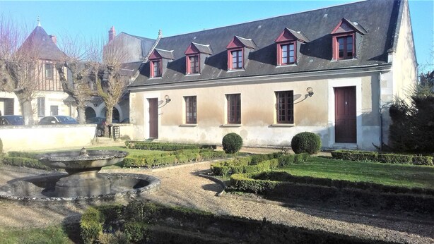 A building with a symmetrical facade, multiple windows with shutters, and a well-maintained garden with a fountain. - cottage of the Small Mass (Amboise)