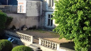 A historic building with a stone facade, a central entrance, and a well-maintained garden with a paved pathway and trimmed hedges. - cottage of the Small Mass (Amboise)