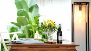 Une table en bois sur laquelle se trouvent une bouteille de vin, deux verres et un vase rempli de fleurs jaunes.