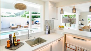 Une cuisine moderne dotée d’une grande fenêtre, d’un évier encastré et d’un coin repas offrant une vue sur l’extérieur.