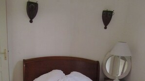 Ein Bett mit weißer Spitze, einem Holzkopfbrett und zwei Wandlampen.