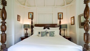 Una cama grande con cabecera de madera y cuatro mesitas de noche, cada una con una lámpara.