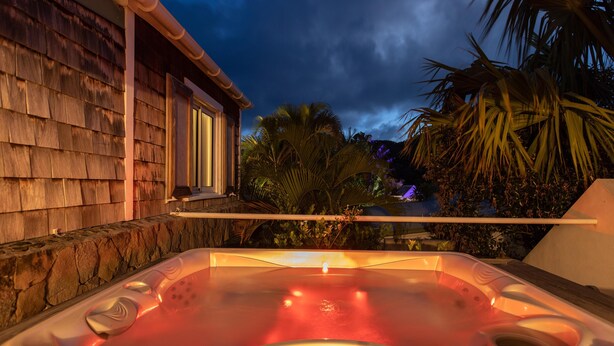 Un jacuzzi con una pared de piedra y un edificio de madera al fondo.