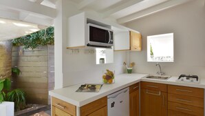 Una cocina moderna con armarios blancos, un microondas integrado, un fregadero y un ventanal.