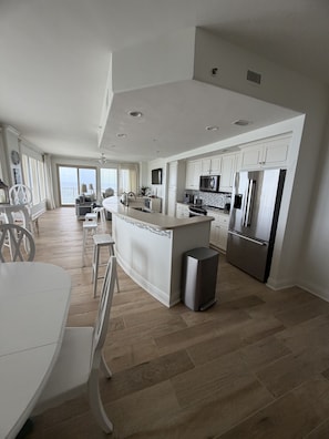 Una cocina amplia con una isla central, muebles blancos y vistas al exterior.