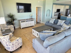 A living room with a grey sofa, patterned armchair, and a TV on the wall.