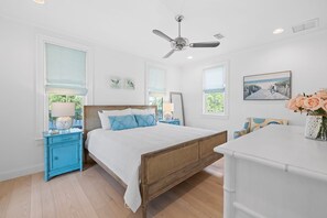 A bedroom with a wooden bed, white walls, and a ceiling fan.