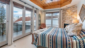 Un dormitorio con una cama grande, un ventilador de techo y una pared de piedra.