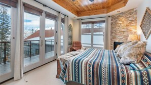 Ein Schlafzimmer mit einem großen Bett, einem Deckenventilator und Blick auf eine verschneite Landschaft durch große Schiebetüren.
