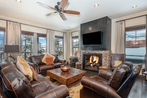 A modern living room with leather sofas, a fireplace, a flat-screen TV, and a ceiling fan. - Cassidy Ridge C-402 Mountain Village Condo (Mountain Village)