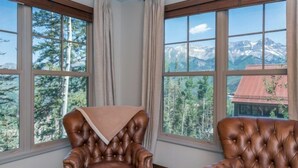 Una habitación con dos sillones de cuero marrón, una ventana con vista a la montaña y una cortina.