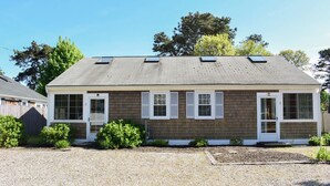 A two-story house with a sloped roof, white shutters, and a small front porch.