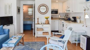 A compact living space with a TV, seating area, kitchenette, and a dining table. - End Unit Condo with breathtaking ocean views! (Dennis Port)