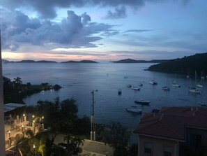 Une vue sur la côte, avec des bateaux ancrés dans des eaux calmes, entourés de collines et sous un ciel dégagé.