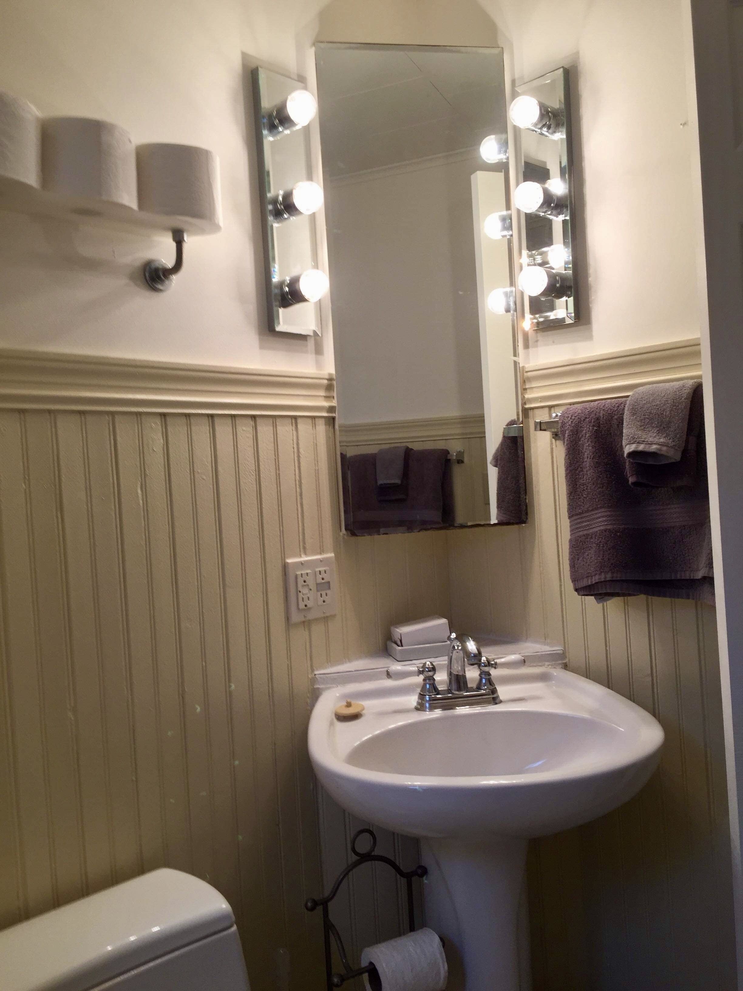 Un baño con lavamanos, espejo e iluminación superior.