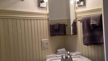 Un baño con lavamanos, espejo e iluminación superior.