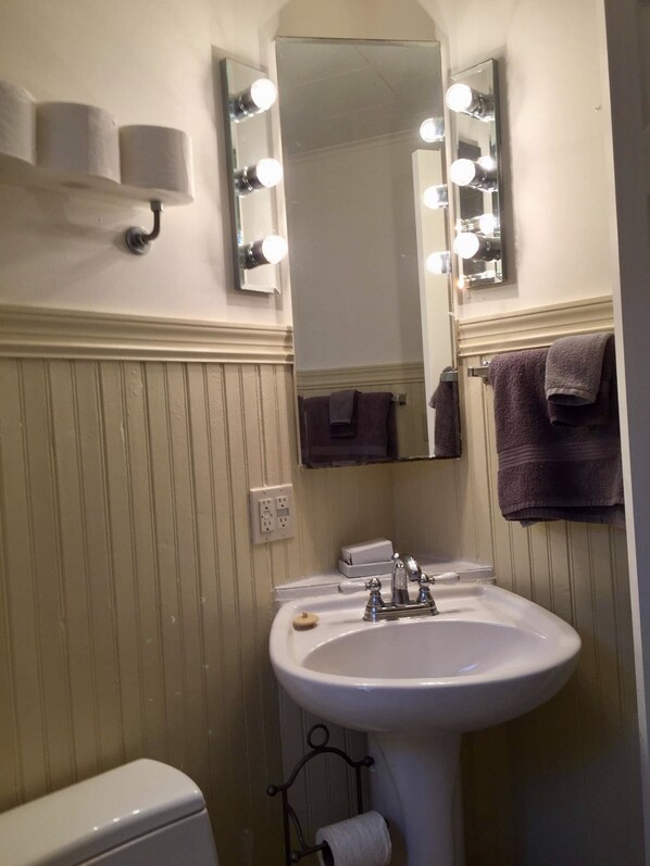 A bathroom with a sink, mirror, and lights above it. - Cute cottage short walk from the beach. (Pentwater)