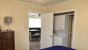 Un dormitorio con cama, cómoda y armario abierto.