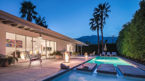 Una casa moderna con piscina, mobiliario exterior y vistas a la montaña.