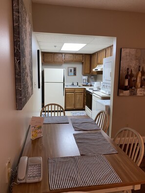 A dining area with a wooden table, striped placemats, and a telephone.