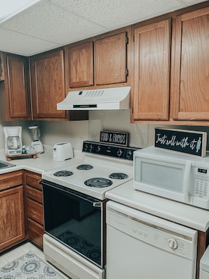 A kitchen with wooden cabinets, a white stove, a microwave, and a toaster.