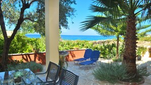 Une terrasse avec une table et des chaises, un palmier et une vue sur la mer.