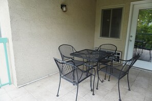 Eine Terrasse mit Tisch, Stühlen, einer Tür und einem Fenster.