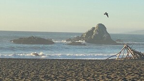 A beach with a rocky outcrop and waves crashing onto the shore.