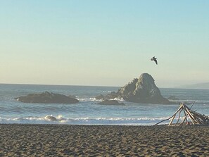 Una playa con un promontorio rocoso y olas rompiendo en la orilla.
