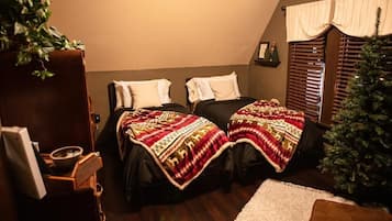 A cozy room with two beds, a small Christmas tree, and a wooden cabinet.