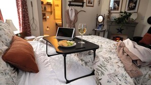 A neatly made bed with a laptop, a glass of white wine, and a plate of snacks on a bedside table. - The Katherine Holle House (Watertown)