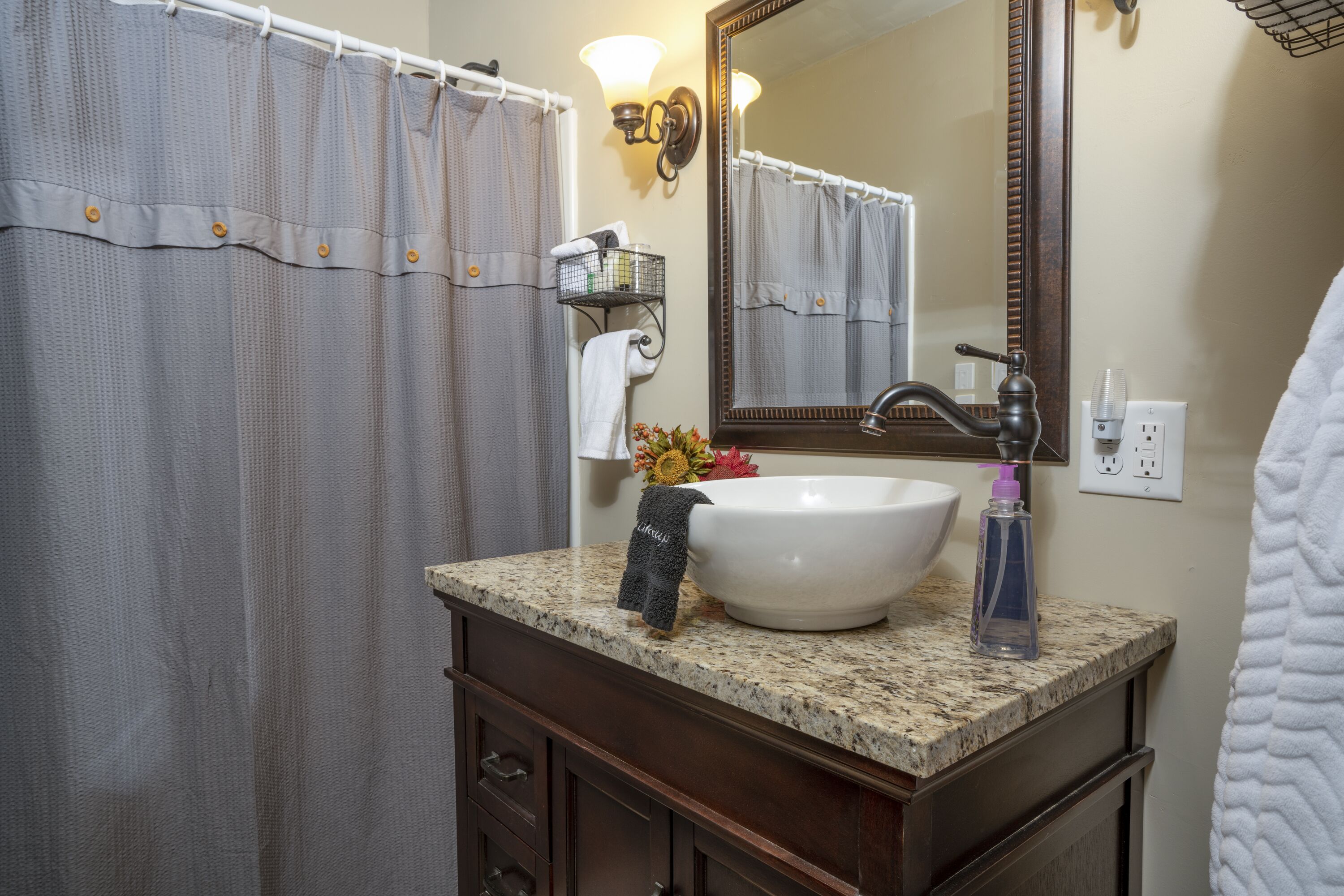 Une salle de bain avec un lavabo blanc, un miroir et un rideau de douche.