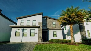 A modern two-story house with a stone facade, a flat roof, and a well-maintained lawn. - Modern 7BR w/Pool/ Minutes from Disney/ ESPN (Kissimmee)