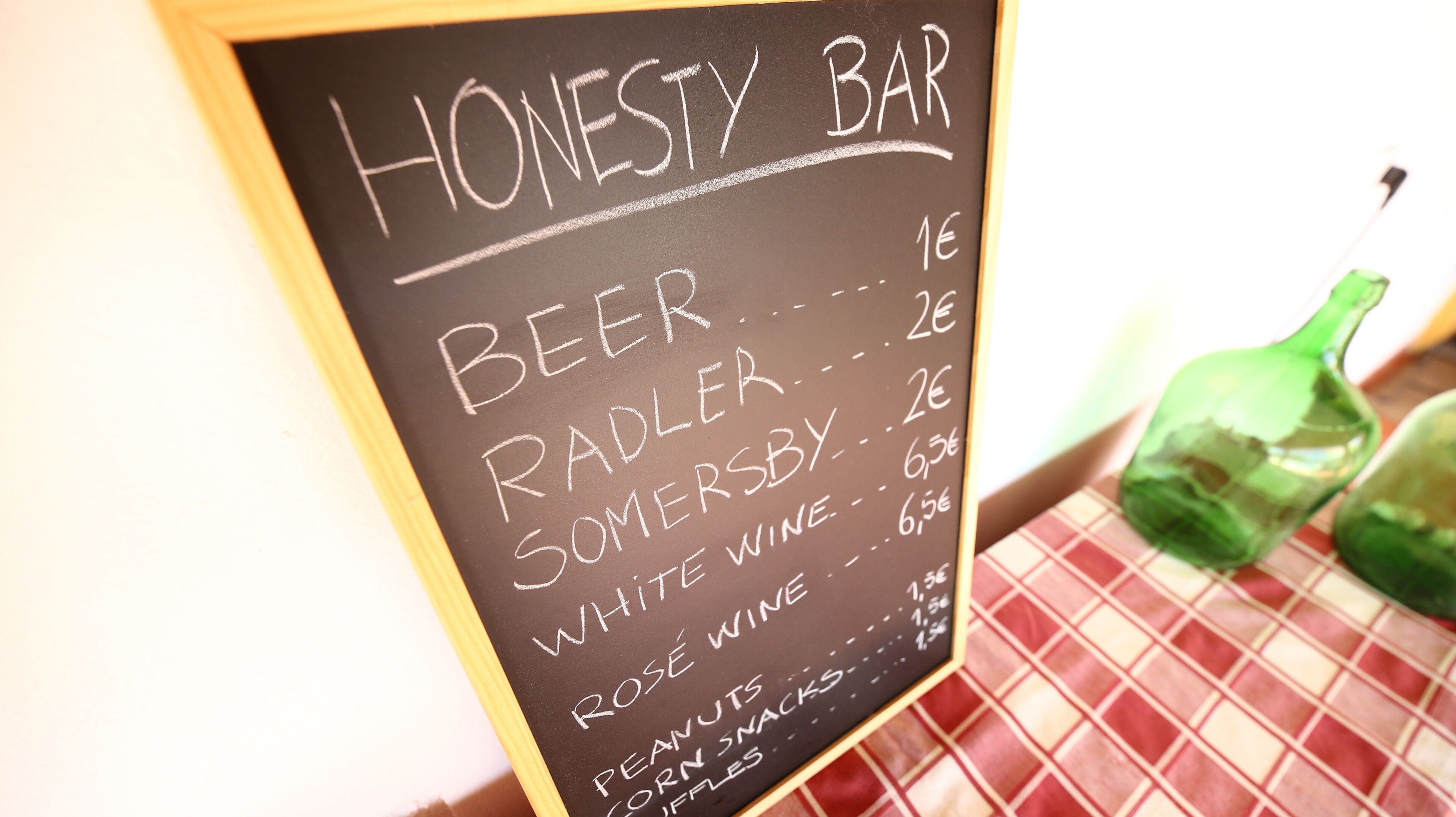 Pizarra con la carta de un bar que incluye cerveza, radler, Somersby, vino blanco, vino rosado, cacahuates, aperitivos de maíz y gofres.