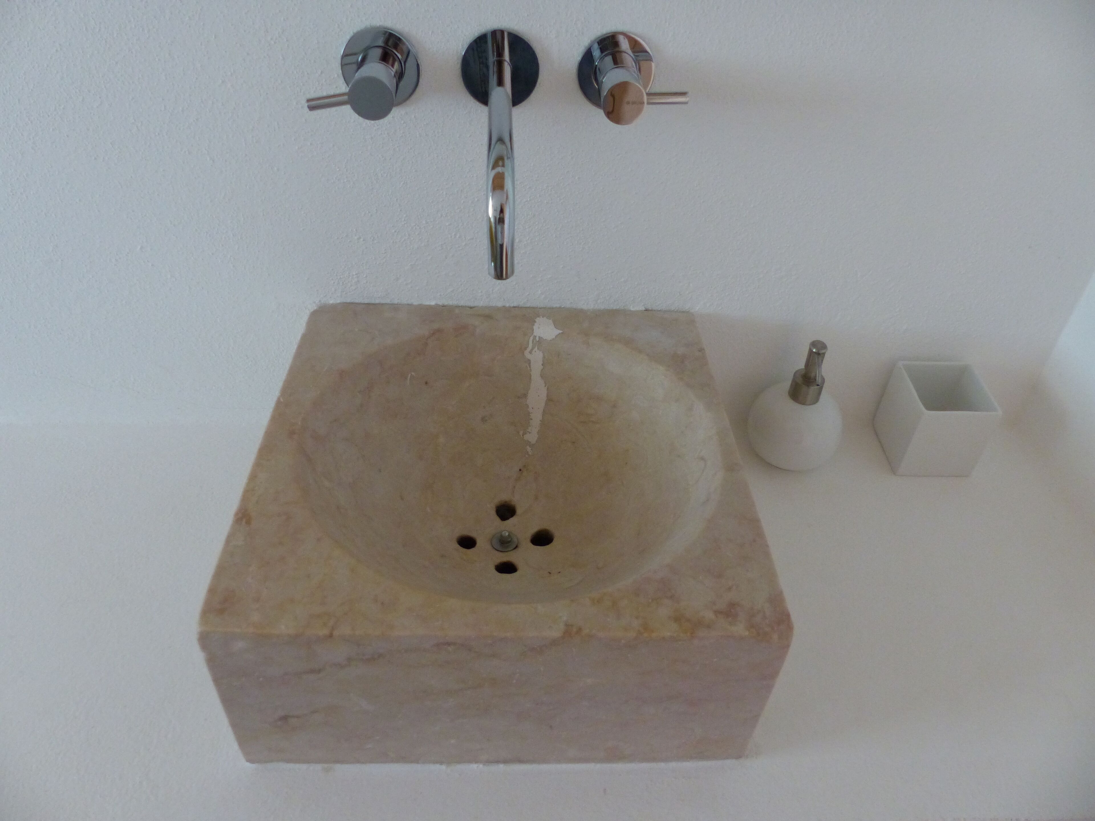 A bathroom sink with a marble basin, a faucet, and a soap dispenser.