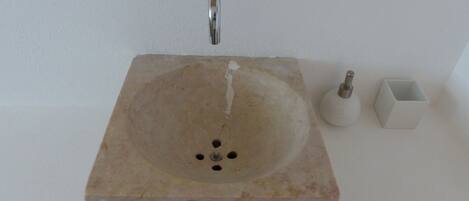 A bathroom sink with a marble basin, a faucet, and a soap dispenser.
