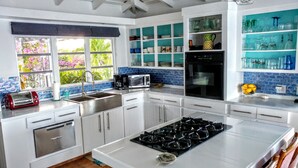 Una cocina moderna con armarios blancos, una estufa a gas, un microondas y un lavavajillas.