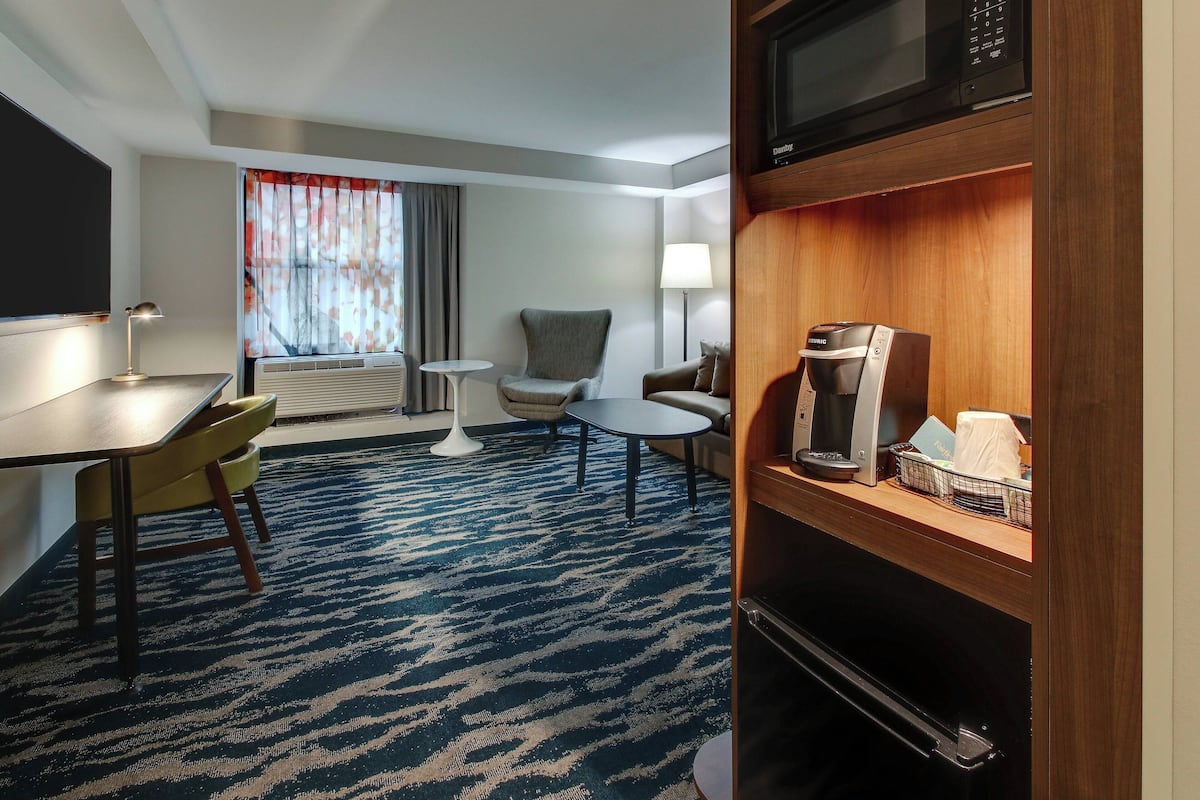 Una habitación de hotel con una mesa de comedor, sillas, un sofá, una cafetera y un microondas.