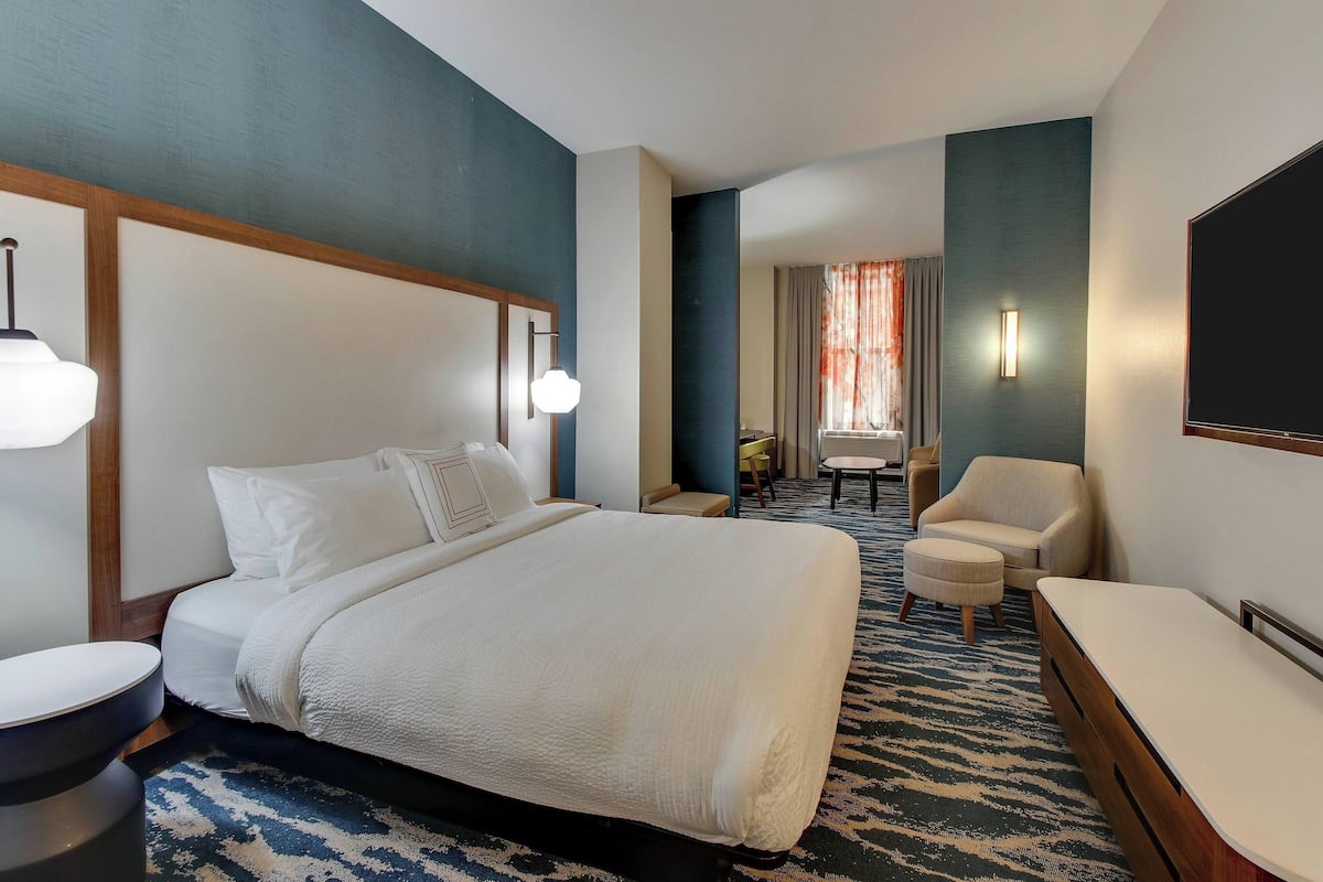 A hotel room with a large bed, a desk, a chair, and a TV.