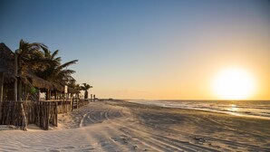 A beach with a wooden fence, palm trees, and a clear sky. - Villa del Mar Praia hotel - Frente a Praia (Camocim)