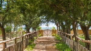 A stone pathway leading to a gated entrance surrounded by trees. - Villa del Mar Praia hotel - Frente a Praia (Camocim)