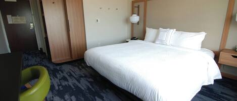 Une chambre d’hôtel avec un grand lit, un bureau, une chaise et une armoire.